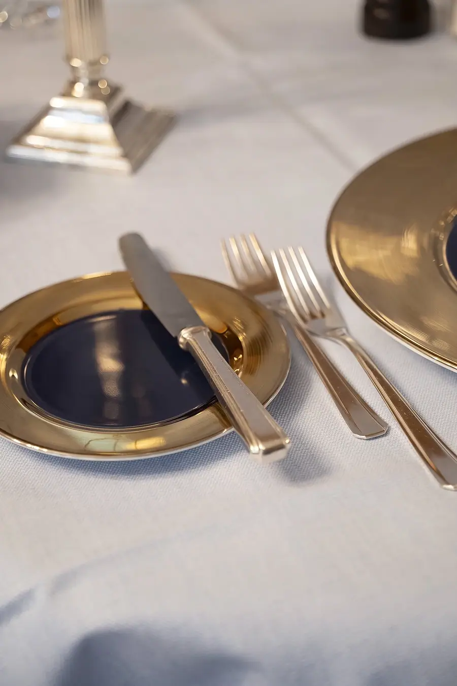 Goldener Teller mit Besteck auf weissem Tuch