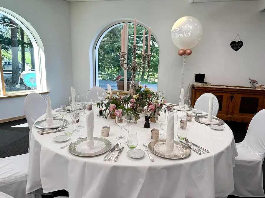 Runder Tisch, für eine Hochzeit gedeckt, mit Blumen und Kerzen