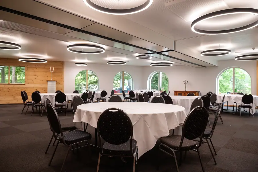 Saal mit runden Tischen und Bogenfenstern